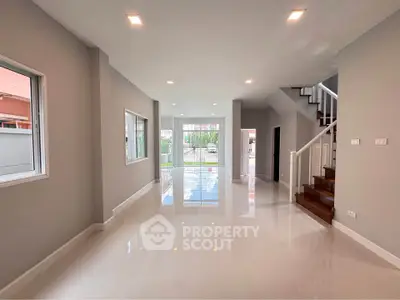 Spacious modern living room with glossy floors and staircase, perfect for family gatherings.