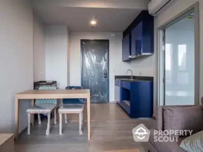 Modern compact apartment interior with blue kitchen cabinets and cozy dining area.