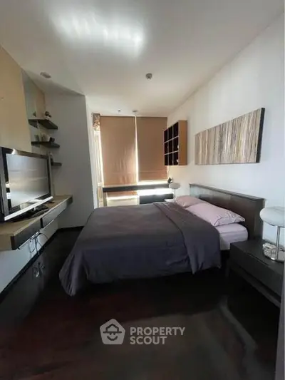 Modern bedroom with sleek design, featuring a cozy bed, wall-mounted TV, and stylish decor.