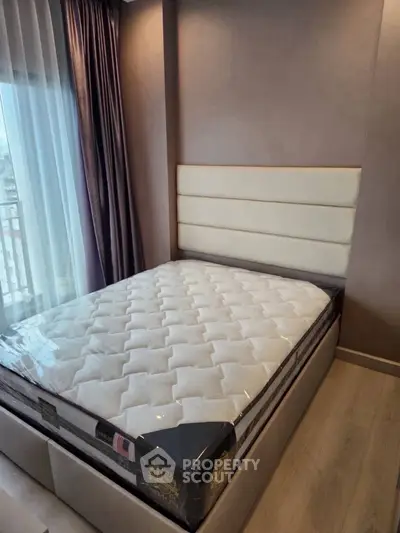 Modern bedroom with plush mattress and elegant headboard, featuring floor-to-ceiling windows and stylish curtains.