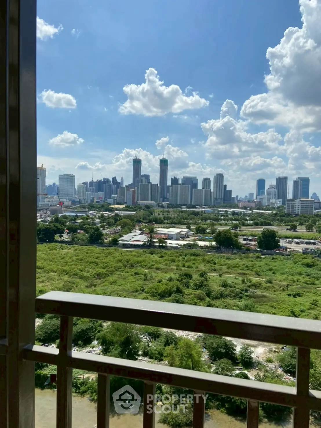 Stunning cityscape view from a high-rise balcony overlooking lush greenery and urban skyline.