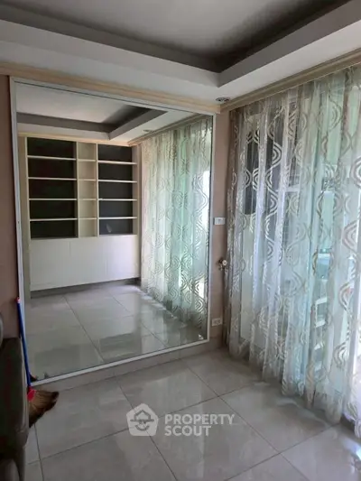 Spacious room with large mirror and elegant curtains, perfect for stylish living.