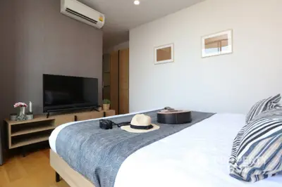 Modern bedroom with stylish decor and natural light, featuring a cozy bed and entertainment setup.