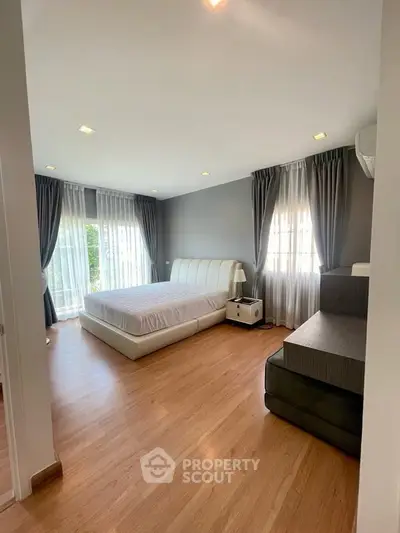 Spacious bedroom with modern decor and large windows for natural light.
