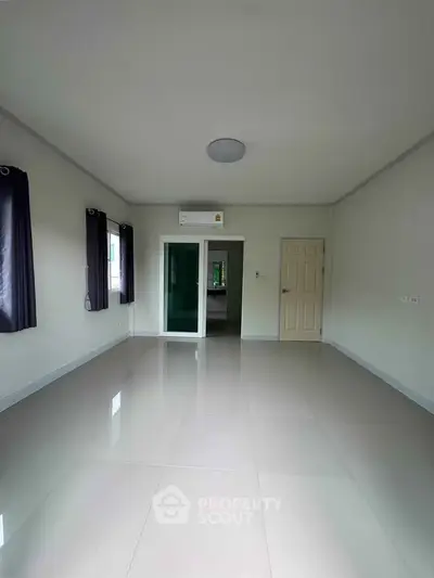 Spacious empty room with glossy tiled floor and large windows, perfect for customization.
