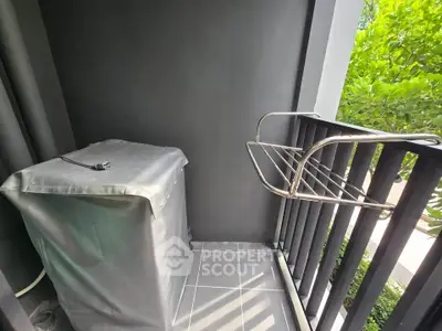 Compact balcony with laundry area and greenery view, perfect for urban living.