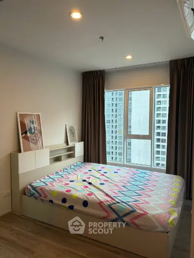 Modern bedroom with large window and stylish decor in high-rise apartment.