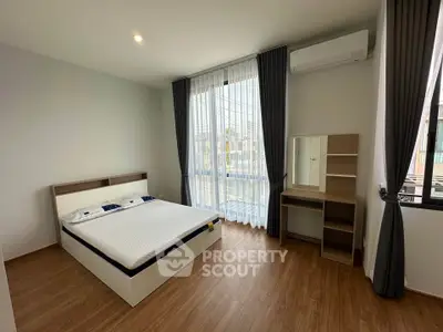 Spacious bedroom with modern furnishings and large window for natural light.