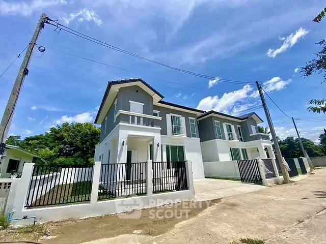 Modern two-story duplex with sleek design and spacious driveway under a clear blue sky.