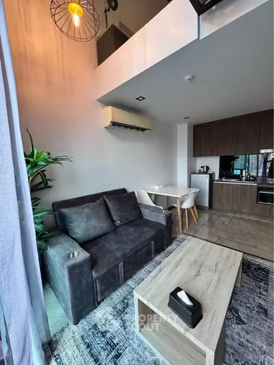 Modern living room with loft, stylish furniture, and open kitchen layout in a chic apartment.