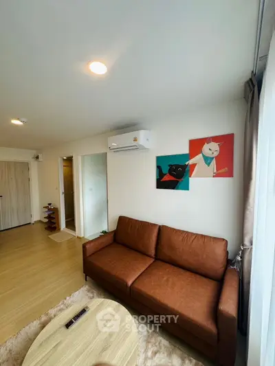 Modern living room with brown sofa, wooden flooring, and stylish wall art.