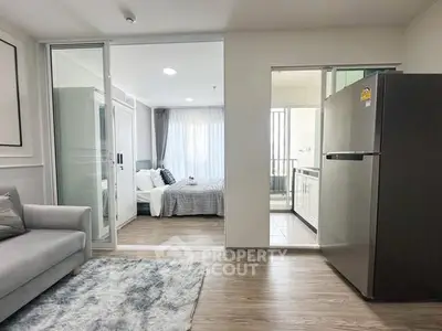 Modern apartment interior with cozy living room, stylish bedroom, and sleek kitchen featuring a large fridge.
