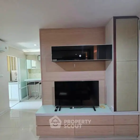 Modern living room with sleek TV unit and open kitchen layout, perfect for contemporary living.