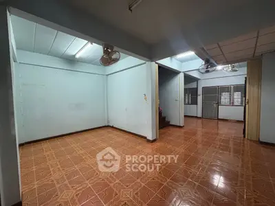 Spacious empty room with tiled flooring and ceiling fans, ideal for customization.