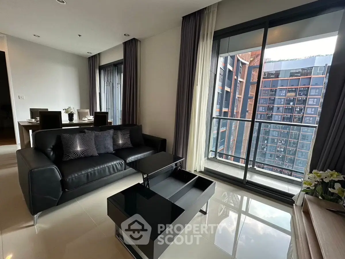 Modern living room with sleek black furniture and city view balcony in luxury apartment.
