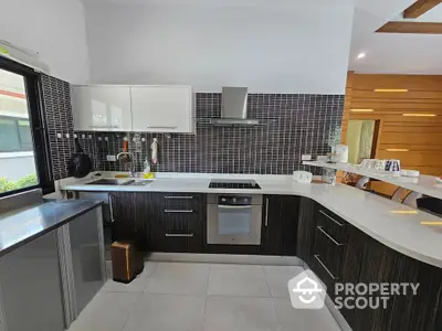 Modern kitchen with sleek cabinetry and built-in oven, featuring open layout and stylish backsplash.