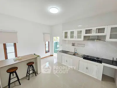 Modern kitchen with sleek white cabinetry and breakfast bar in bright open space.