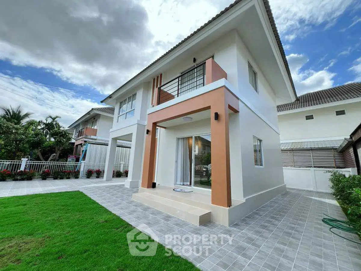 Modern two-story house with spacious tiled patio and lush green lawn.