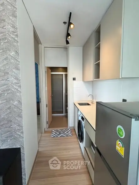 Modern compact kitchen with integrated appliances and sleek cabinetry in a stylish apartment.