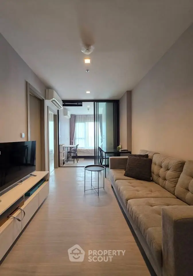 Modern living room with sleek furniture and open layout leading to dining area.