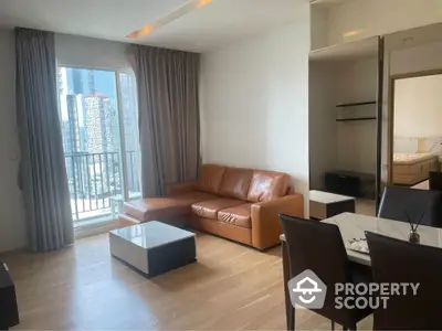 Modern living room with leather sofa and city view balcony in high-rise apartment.