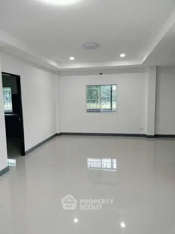 Spacious empty room with glossy tiled floor and large window, ideal for customization.