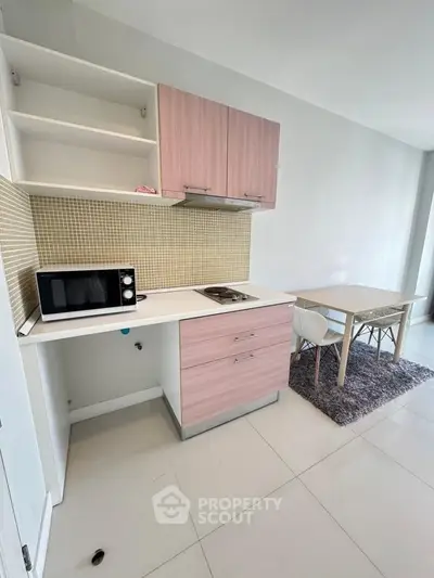 Modern kitchen with sleek cabinets and dining area, featuring a microwave and stylish decor.