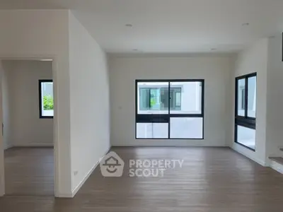 Spacious modern living room with large windows and wooden flooring, perfect for natural light lovers.