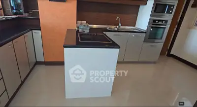 Modern kitchen with sleek cabinetry and built-in appliances, featuring a central island and glossy flooring.