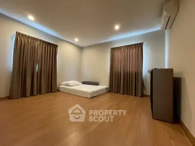 Spacious minimalist bedroom with wooden flooring and natural light