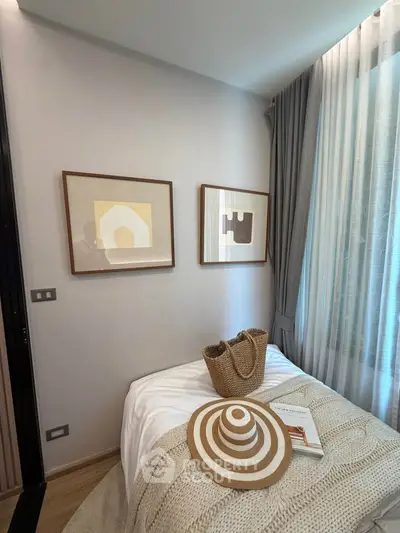 Cozy bedroom with stylish decor and natural light, featuring framed art and elegant curtains.