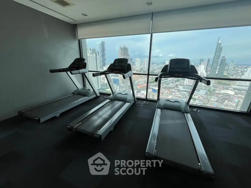 Modern gym with treadmills and stunning city skyline view through large windows.