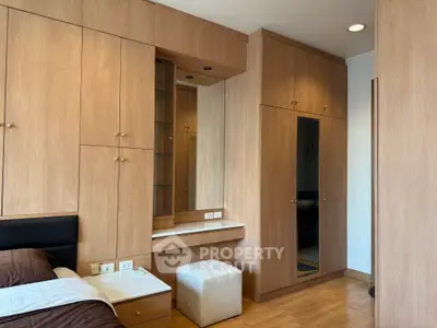 Spacious bedroom with elegant wooden built-in wardrobes and cozy seating area.