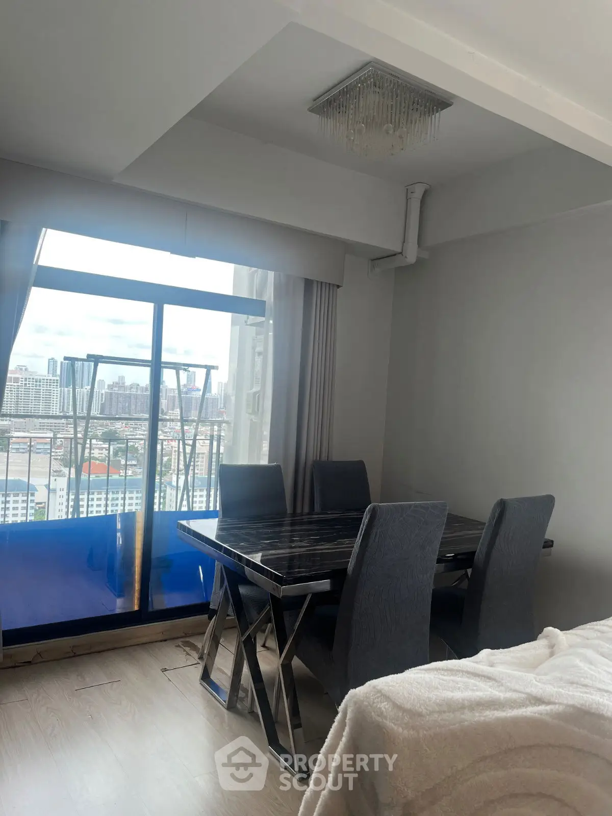 Modern dining area with city view from high-rise apartment balcony.