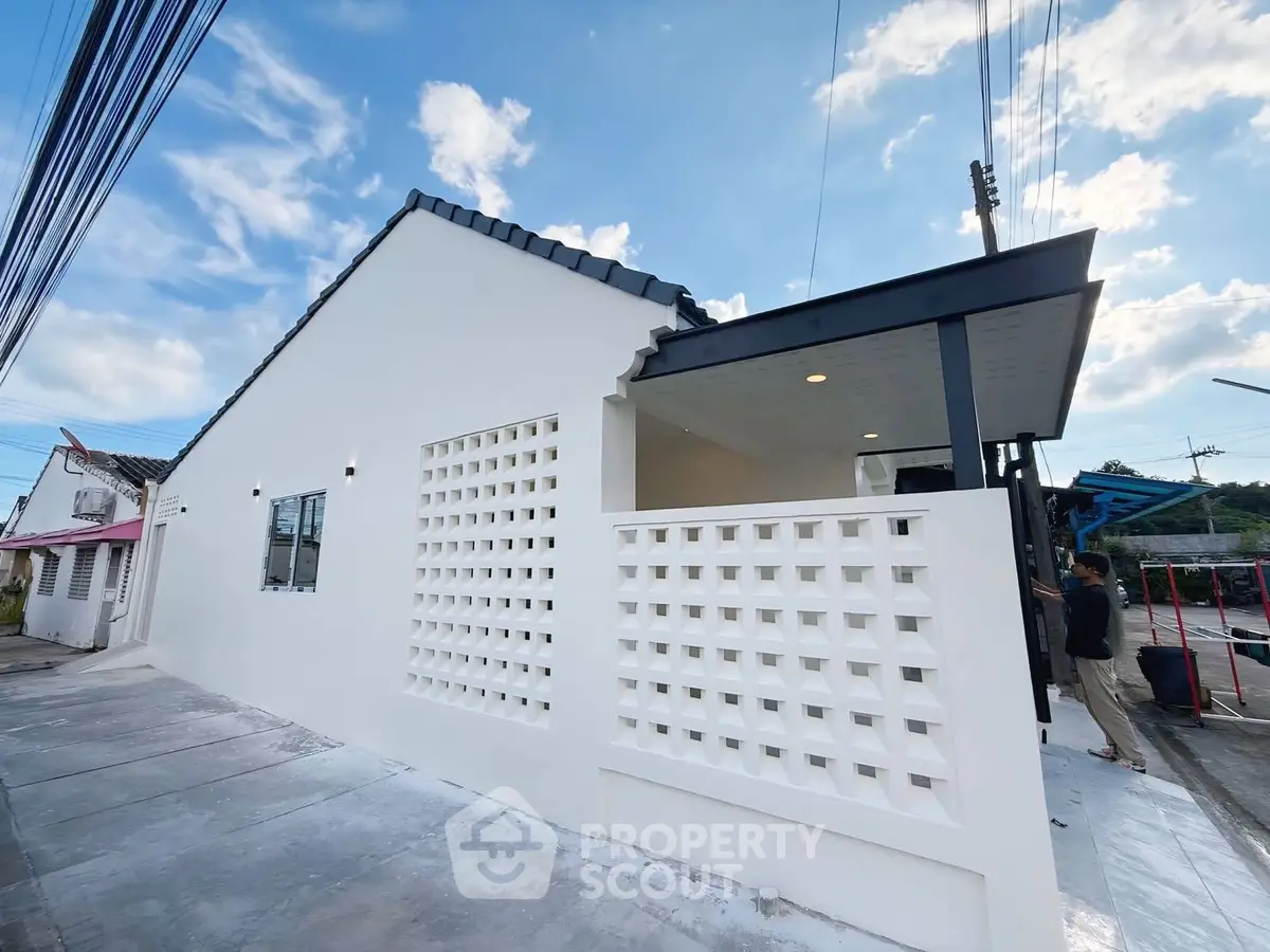 Modern white exterior house with unique lattice wall and sleek roof design.