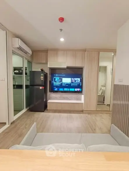 Modern living room with sleek design, featuring a wall-mounted TV and stylish kitchen area.