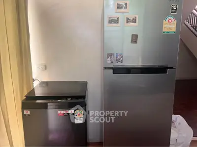 Modern kitchen with stainless steel fridge and compact washing machine, perfect for efficient living.