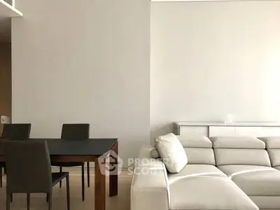 Modern living room with sleek furniture and neutral tones, featuring a stylish dining area and comfortable seating.