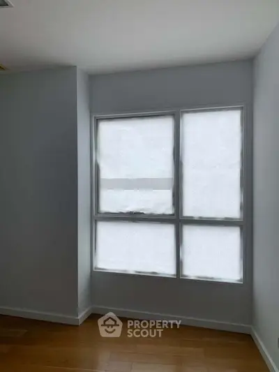 Minimalist room with large window and wooden flooring, perfect for natural light lovers.