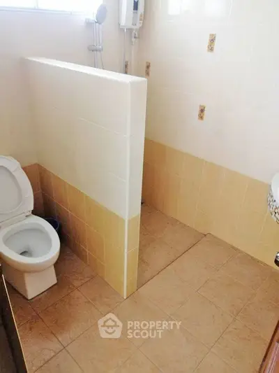 Compact bathroom with tiled walls and floor, featuring a toilet and shower area.