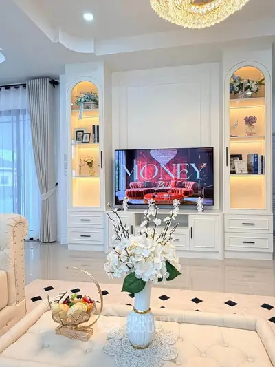 Elegant living room with built-in shelves, modern decor, and a stylish chandelier, perfect for luxury living.