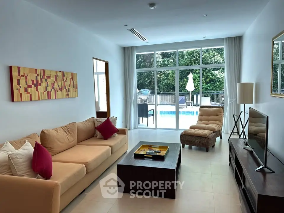 Spacious living room with pool view, modern furniture, and large windows for natural light.