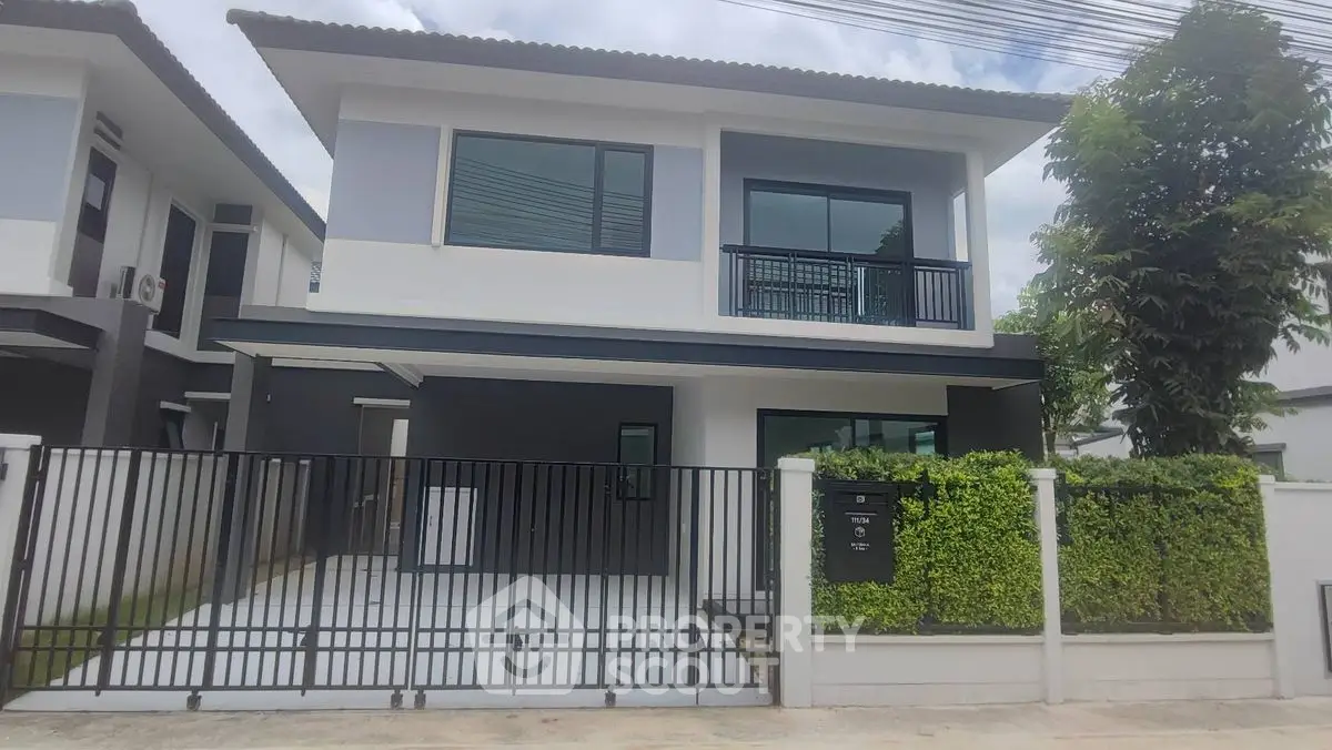 Modern two-story house with gated entrance and lush greenery