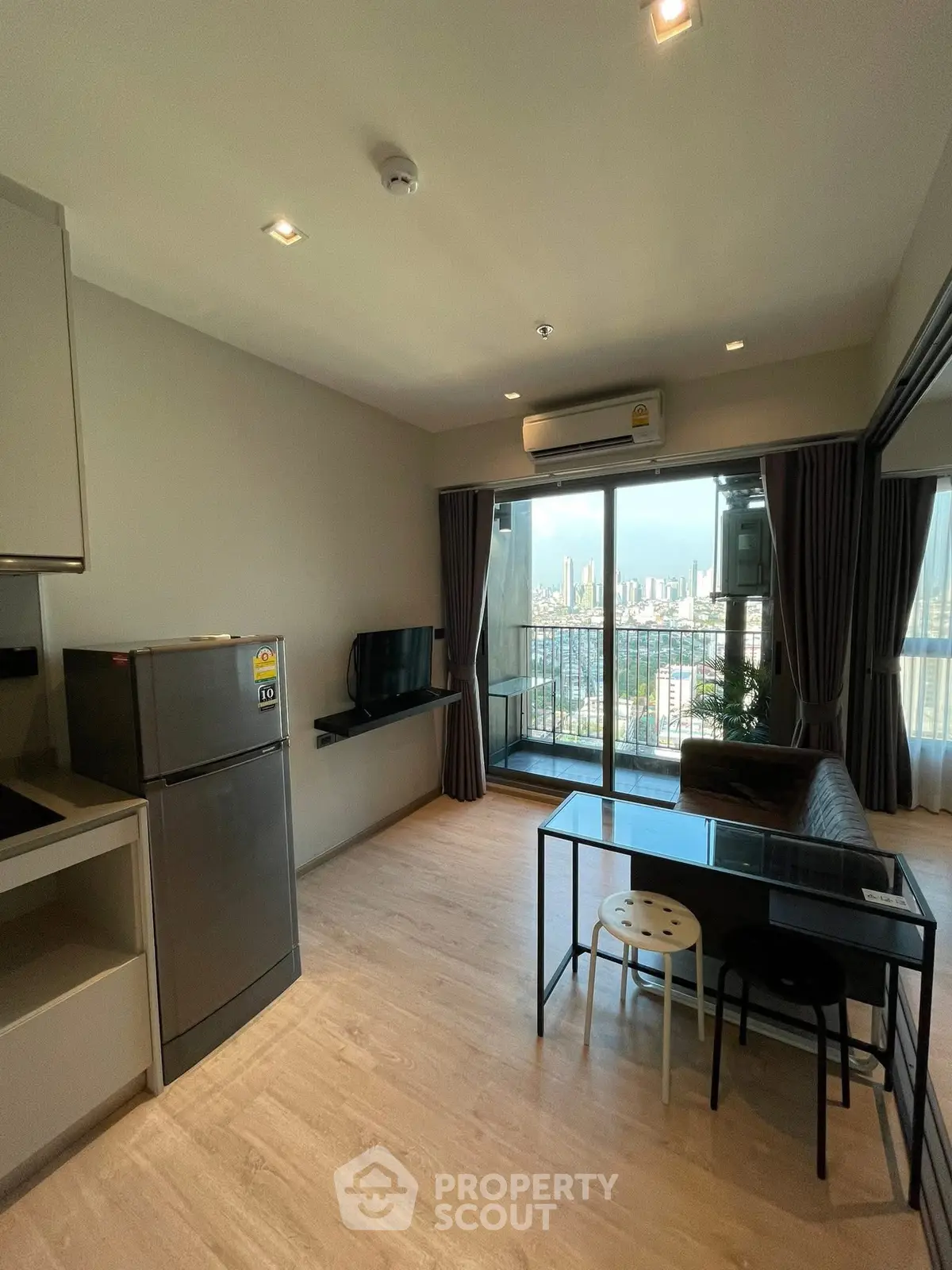 Modern living room with balcony and city view, featuring sleek furniture and natural light.