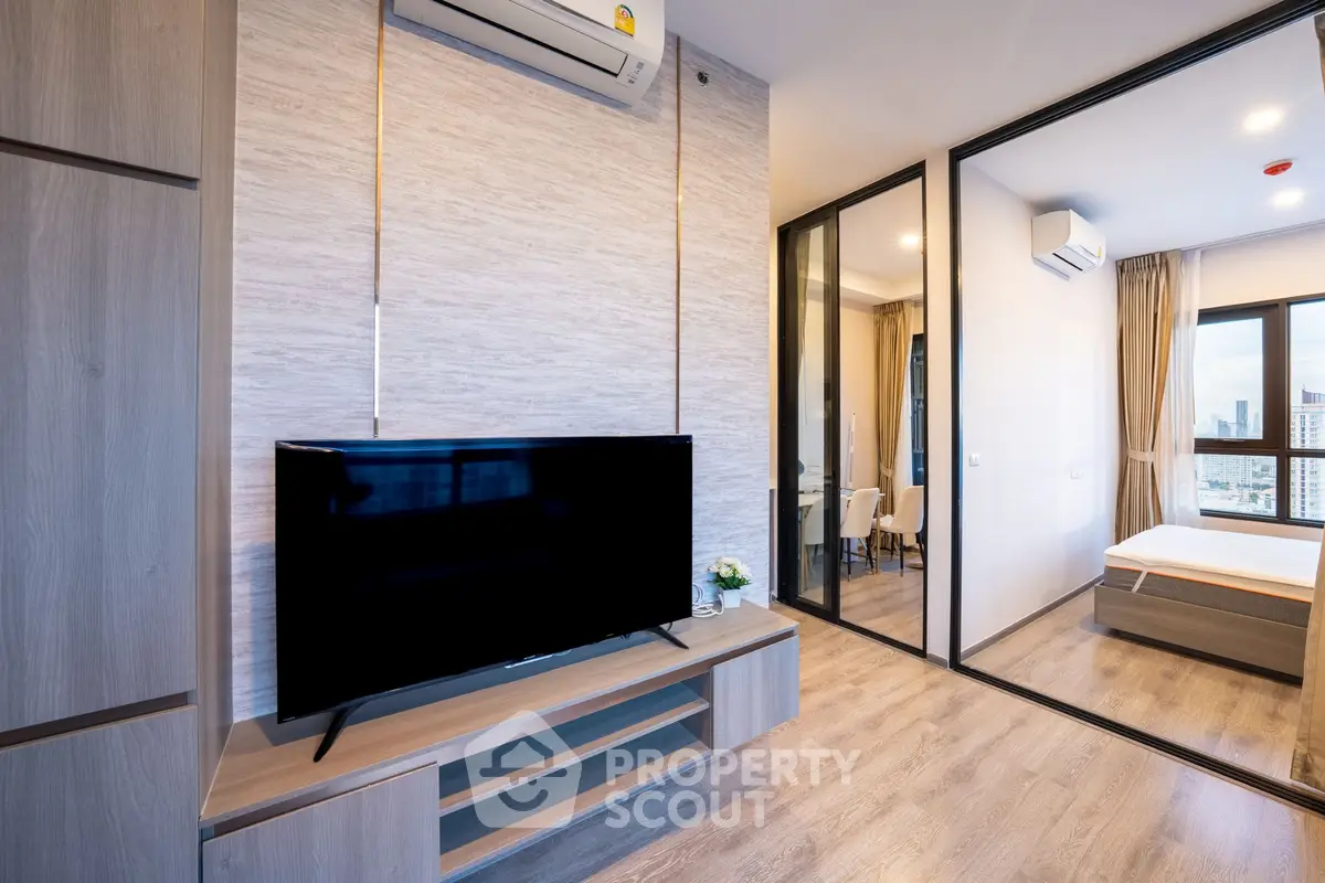 Modern apartment interior with TV and bedroom view, featuring sleek design and natural light.