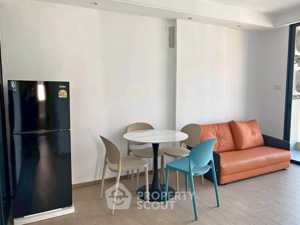 Modern living room with sleek furniture and natural light, featuring a compact dining area and stylish sofa.