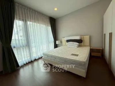 Spacious bedroom with large window and elegant curtains, featuring a comfortable bed and modern decor.