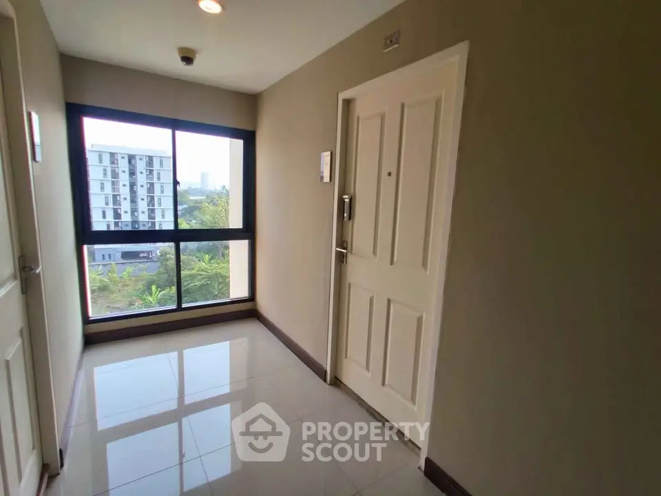 Bright apartment hallway with large window and glossy tiled floor