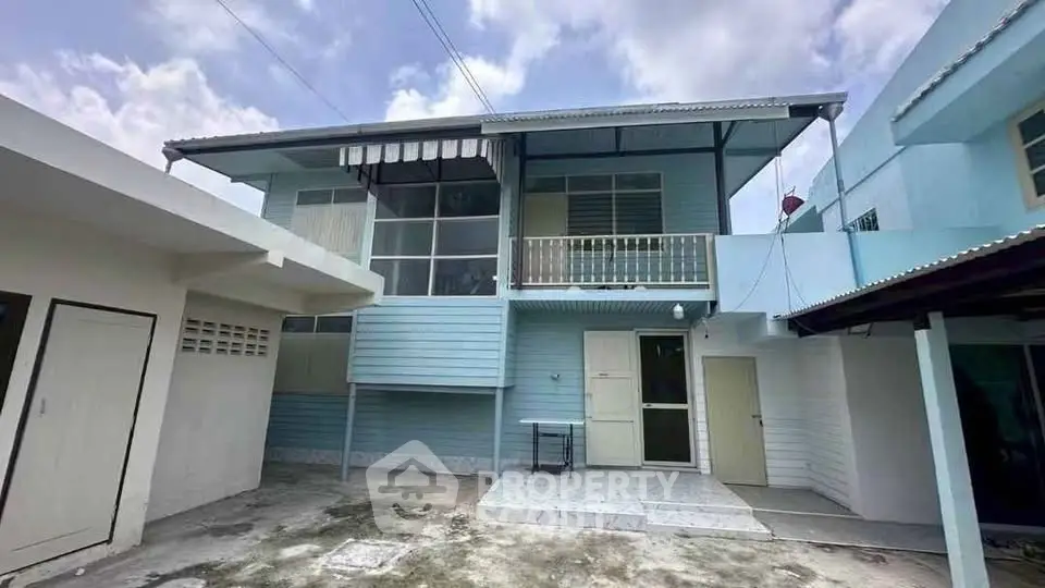 Charming two-story blue house with balcony and spacious exterior, perfect for family living.