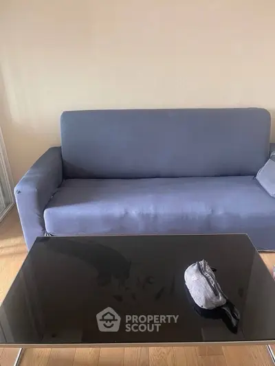 Modern living room with sleek black glass coffee table and stylish gray sofa on wooden flooring.